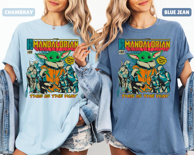 May include: Light blue and blue jean t-shirts featuring a graphic of The Mandalorian comic book cover. The design includes the character Grogu, Stormtroopers, and the text "THIS IS THE WAY". The shirts are labeled "CHAMBRAY" and "BLUE JEAN".