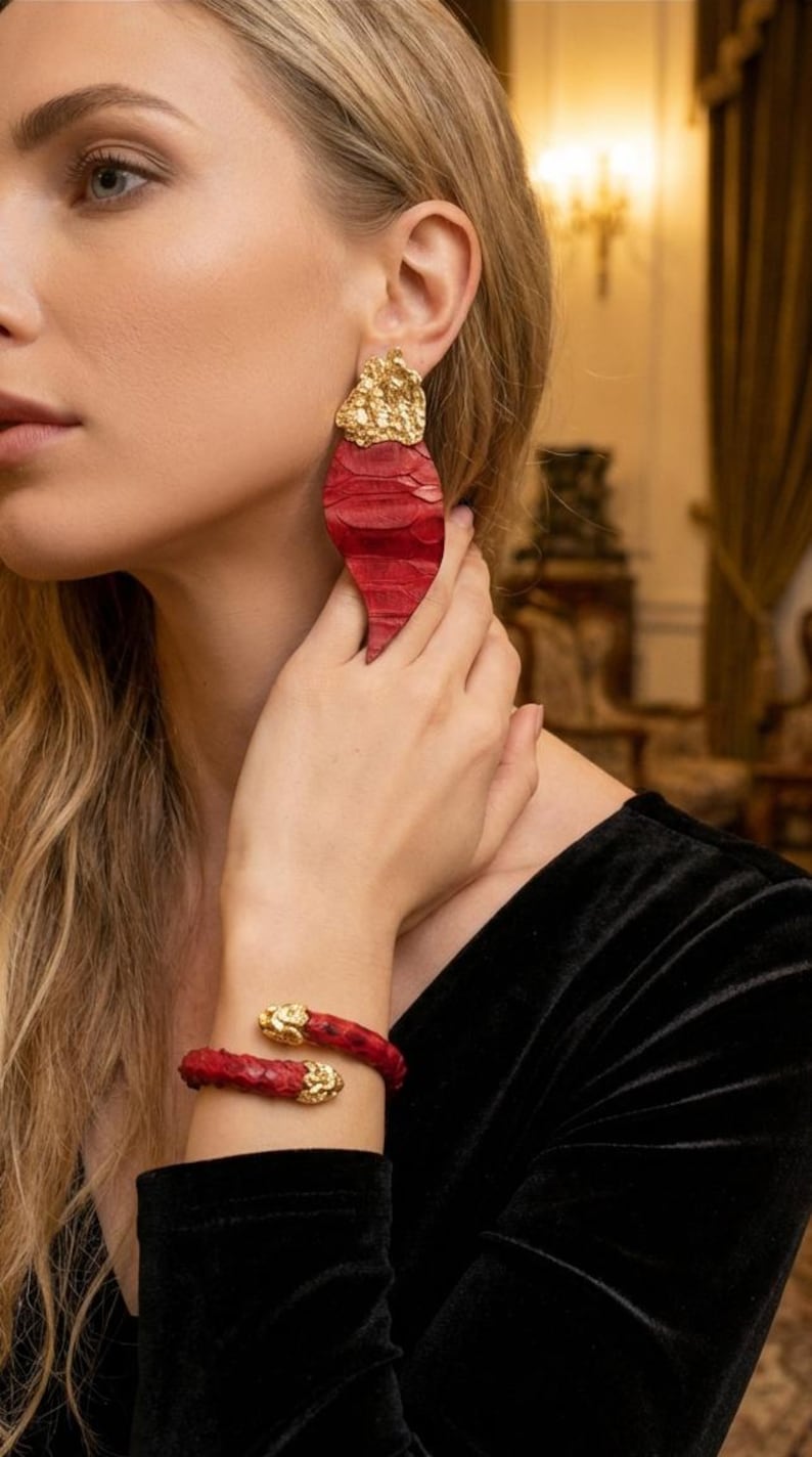 Puede incluir: Juego de joyas rojas y doradas. El conjunto incluye un par de pendientes grandes en forma de l&aacute;grima y una pulsera de pu&ntilde;o a juego. Los pendientes y la pulsera presentan un material rojo texturizado con detalles dorados.