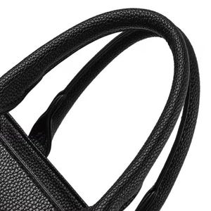 May include: Close-up of a black handbag with textured leather. The curved handles are thick and sturdy, designed for comfortable carrying. The bag's design suggests a classic, elegant style.