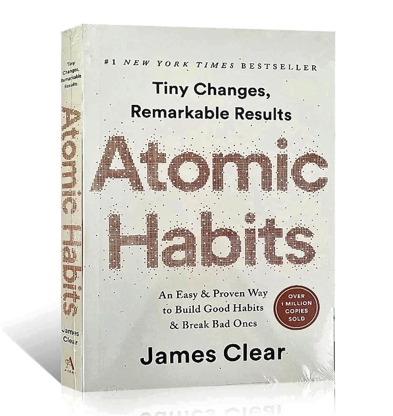 Peut inclure: Un livre &agrave; couverture rigide intitul&eacute; "Atomic Habits" de James Clear. La couverture est blanche avec le titre en grandes lettres marron pix&eacute;lis&eacute;es. Le texte "Tiny Changes, Remarkable Results" est au-dessus du titre. Le livre est emball&eacute; dans du plastique transparent.