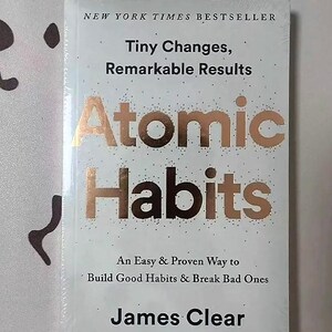 Peut inclure: Livre blanc intitul&eacute; "Atomic Habits" avec des lettres dor&eacute;es. Le livre est un best-seller du New York Times et comprend le nom de l'auteur, James Clear. La couverture indique &eacute;galement "Tiny Changes, Remarkable Results".