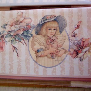 Pode incluir: Uma menina com cabelo loiro e um chap&eacute;u rosa e azul segura um urso de peluche. Ela est&aacute; cercada por flores rosa e brancas. O fundo &eacute; um padr&atilde;o listrado rosa e branco.