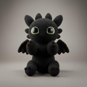 Può includere: Un peluche a forma di drago nero fatto a mano all'uncinetto, con grandi occhi espressivi e piccole ali. Il drago ha un aspetto amichevole, perfetto per un giocattolo per bambini o un oggetto da collezione. Il peluche è seduto, mostrando il dettagliato lavoro all'uncinetto.