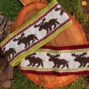 May include: A knitted headband featuring a repeating pattern of brown moose silhouettes on a cream background, bordered by lime green and dark red stripes. The design includes intricate geometric details along the edges of the stripes.