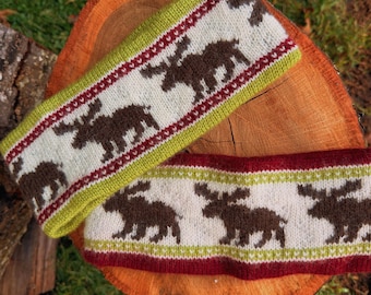 May include: A knitted headband featuring a repeating pattern of brown moose silhouettes on a cream background, bordered by lime green and dark red stripes. The design includes intricate geometric details along the edges of the stripes.