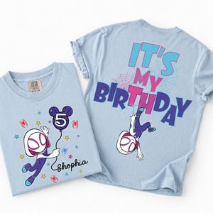 May include: Two light blue t-shirts. One features a cartoon character holding a balloon with the number 5 and the name "Shophia". The other shirt has the text "IT'S MY BIRTHDAY" and a character graphic. Both shirts have a spider-web design.