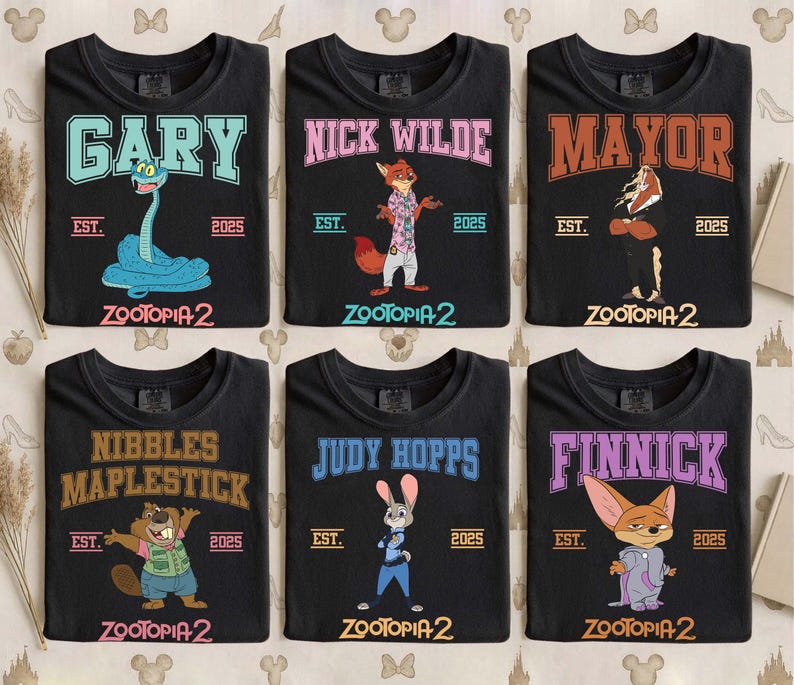 K&ouml;nnte beinhalten: Sechs schwarze T-Shirts mit Charakteren aus Zootopia 2. Jedes Shirt hat einen Charakternamen in einer College-Schriftart, den Text "EST. 2025" und den Filmtitel. Zu den Charakteren geh&ouml;ren Gary, Nick Wilde, Mayor, Nibbles Maplestick, Judy Hopps und Finnick.