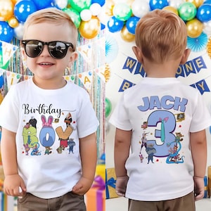 May include: A white t-shirt with the word "Birthday" above the word "BOY" in colorful letters, with cartoon characters. The back of the shirt says "JACK 3" in blue and purple, with cartoon characters. The boy is wearing sunglasses.
