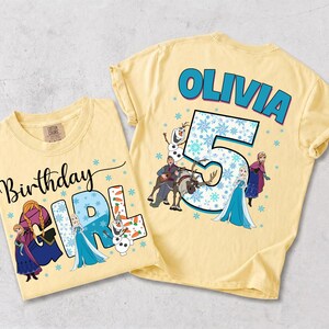 Puede incluir: Dos camisetas de color amarillo p&aacute;lido con personajes de Frozen. Una muestra el texto Birthday GIRL con Anna, Elsa y Olaf. La otra muestra el nombre OLIVIA sobre un n&uacute;mero 5 grande, rodeado por Anna, Elsa, Kristoff, Sven y Olaf.