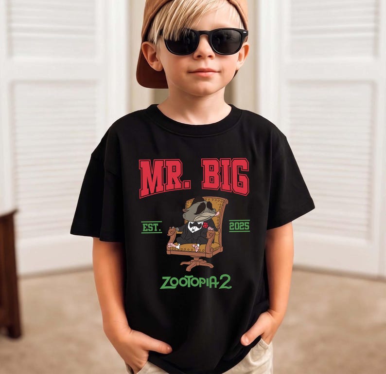 K&ouml;nnte beinhalten: Schwarzes T-Shirt mit dem Text "MR. BIG" in Rot und Wei&szlig; und "EST. 2025" darunter. Eine Zeichentrickfigur im Anzug sitzt in einem Stuhl. Das Shirt hat auch den Text "ZOOTOPIA 2" in Gr&uuml;n.