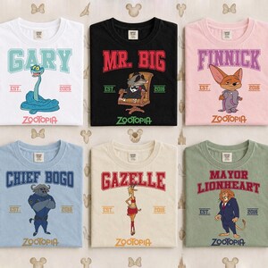 May include: Six t-shirts featuring characters from Zootopia. Each shirt displays a character's name in a collegiate font, along with the word "Zootopia" and the year "2016" or "2025". The shirts are in various colors, including white, black, pink, blue, beige, and green.