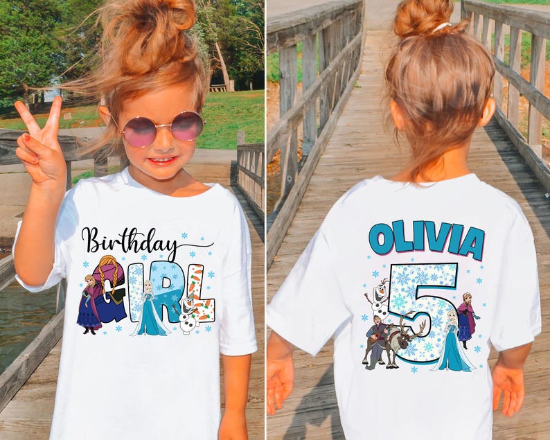Puede incluir: Una camiseta blanca con un gr&aacute;fico frontal con el texto Birthday Girl e ilustraciones de personajes de Frozen. El gr&aacute;fico trasero muestra el nombre Olivia, el n&uacute;mero 5 y otras ilustraciones de personajes con detalles de copos de nieve.