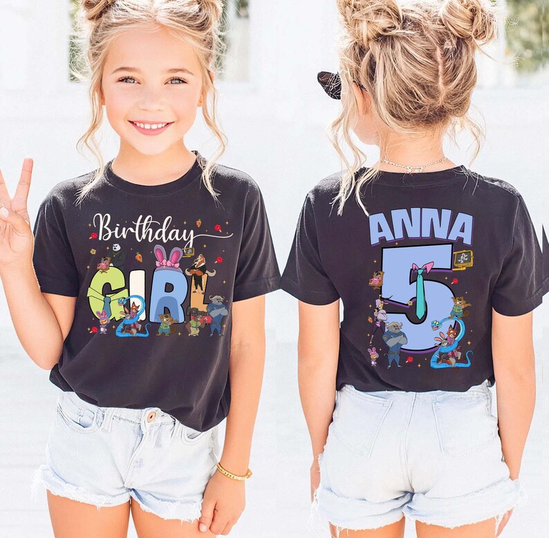 May include: Black t-shirt with the words "Birthday Girl" and a colorful graphic. The back of the shirt has the name "Anna" and the number "5". The shirt is worn by a young girl.
