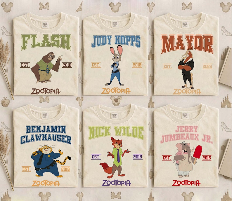 May include: Six off-white t-shirts featuring characters from the movie "Zootopia." Each shirt has a character's name in a collegiate font, the word "Zootopia," and the year "2016." Characters include Flash, Judy Hopps, Mayor, Benjamin Clawhauser, Nick Wilde, and Jerry Jumbeaux Jr.