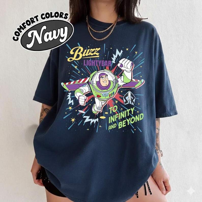 May include: Navy blue t-shirt with a graphic of Buzz Lightyear, the text reads "Buzz Lightyear" and "To Infinity and Beyond." The shirt has a Comfort Colors label.