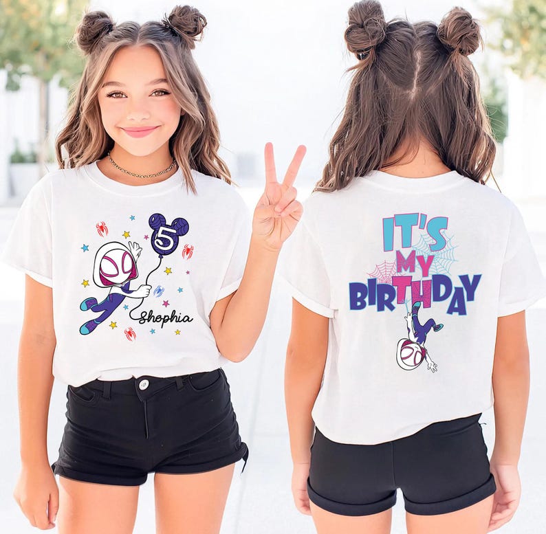 May include: White t-shirt with a colorful graphic featuring a cartoon character holding a balloon with the number 5. The front of the shirt has the name "Shopia". The back of the shirt says "It's My Birthday".