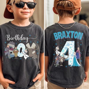 Puede incluir: Una camiseta gris carb&oacute;n de manga corta con un gr&aacute;fico frontal que incluye el texto Birthday Boy y personajes de Frozen. El gr&aacute;fico trasero muestra el nombre Braxton, el n&uacute;mero 4 y personajes de Frozen, decorados con copos de nieve azules.