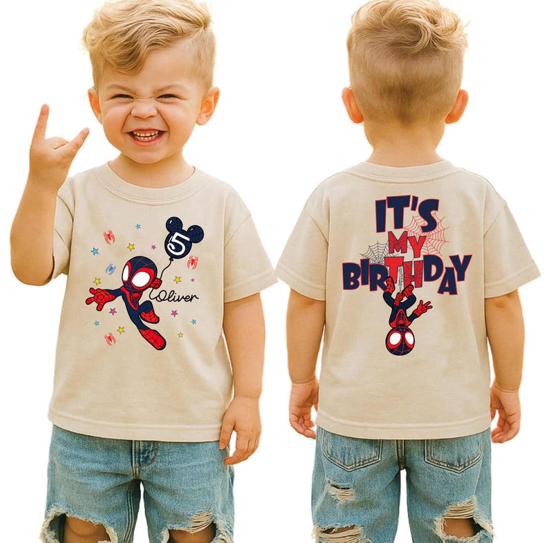 May include: A beige t-shirt featuring a Spider-Man design holding a balloon with the number 5 and the name "Oliver". The back of the shirt says "It's My Birthday" with a Spider-Man graphic. The shirt is worn by a child.
