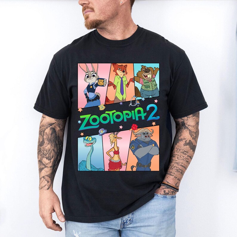 May include: Black t-shirt featuring a colorful graphic of characters from the animated movie Zootopia 2. The design includes Judy Hopps, Nick Wilde, and other characters. The words "Zootopia 2" are in green and blue.