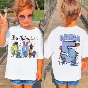 May include: A white t-shirt with the words "Birthday Girl" and a colorful graphic on the front. The back of the shirt has the name "Anna" and the number "5" in blue. The girl is wearing sunglasses and denim shorts.