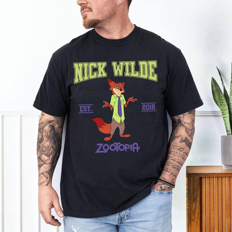 May include: Black t-shirt featuring Nick Wilde from Zootopia. The design includes the text "NICK WILDE" in green, "EST. 2016", and "ZOOTOPIA" in purple. The cartoon fox is wearing a green shirt, purple tie, and brown pants.