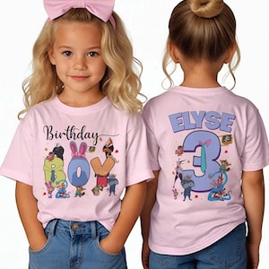 May include: Two light pink t-shirts with a birthday theme. The front shirt says "Birthday BOY" with cartoon characters. The back shirt says "ELYSE 3" with cartoon characters. The shirts are worn by a young girl.
