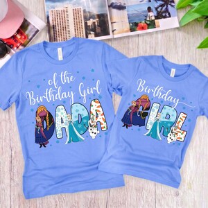 Puede incluir: Dos camisetas azul claro con los personajes de Frozen, Anna, Elsa y Olaf. La camiseta m&aacute;s grande muestra el texto of the Birthday Girl DADA, mientras que la m&aacute;s peque&ntilde;a muestra Birthday GIRL, ambas decoradas con copos y zanahorias.