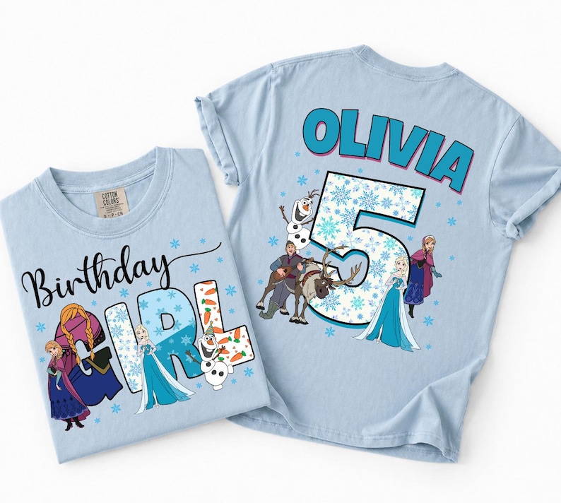 Puede incluir: Dos camisetas azul claro con personajes de Frozen. Una dice Birthday GIRL con Anna, Elsa y Olaf. La otra dice OLIVIA y el n&uacute;mero 5 con Anna, Elsa, Olaf, Kristoff y Sven, todo rodeado de copos de nieve azules estampados en la tela.