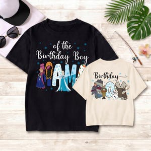 Puede incluir: Una camiseta negra con el texto of the Birthday Boy MAMA e ilustraciones de Anna y Elsa, junto a una camiseta color crema con el texto Birthday BOY e ilustraciones de Kristoff, Olaf y Sven, ambas con detalles de copos de nieve azules.