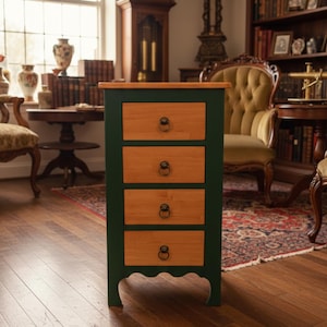 May include: A four-drawer wooden cabinet with a dark green frame and natural wood-tone drawers. The cabinet has a rectangular shape with a scalloped base and ring pulls on each drawer. The top of the cabinet is a natural wood tone.