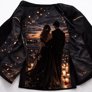 Peut inclure: Veste noire avec une doublure en satin représentant un couple sur un balcon au coucher du soleil, entouré de bougies. La veste a des fermetures éclair dorées et une coupe classique, idéale pour les occasions formelles.