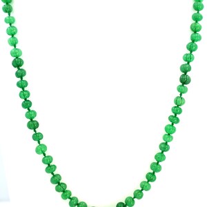 May include: A vibrant green beaded necklace against a white background. The necklace features numerous small, round beads with a textured surface, strung together to form a long strand. The beads are a consistent, bright green color.