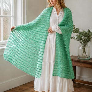 May include: A bright green, open-knit shawl with a textured, airy appearance. The rectangular wrap features a consistent horizontal striped pattern throughout the fabric, showcasing a lightweight, semi-sheer construction with a soft, fuzzy finish.