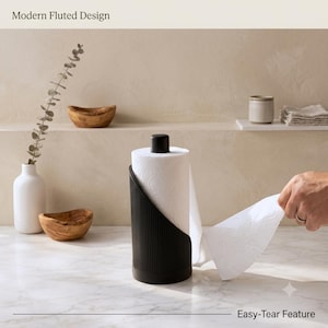 Peut inclure: Un porte-essuie-tout noir au design cannelé moderne avec une fonction de déchirure facile. Le support cylindrique présente une texture nervurée verticale et un capuchon supérieur noir, maintenant un rouleau de papier blanc sur un marbre.