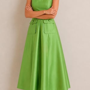 May include: A sleeveless lime green midi dress featuring a round neckline, a fitted bodice, and a flared skirt. The dress includes two front patch pockets at the waist, each adorned with a single matching button, and a smooth, structured fabric finish.