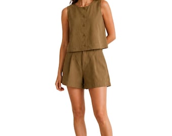 Puede incluir: Un conjunto de dos piezas verde oliva que consta de una parte superior sin mangas con botones y pantalones cortos de cintura alta. El conjunto está hecho de una tela ligera. El modelo lleva sandalias de cuero marrón.