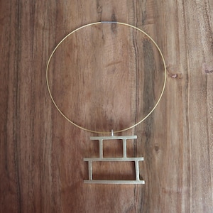 May include: A gold necklace with a geometric pendant. The pendant is made of three stacked rectangular shapes.