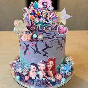 May include: A decorated birthday cake with a purple base and a variety of decorations. The cake features a topper with the number 5 and the name "Luca". Additional decorations include disco balls, stars, and images of cartoon characters.