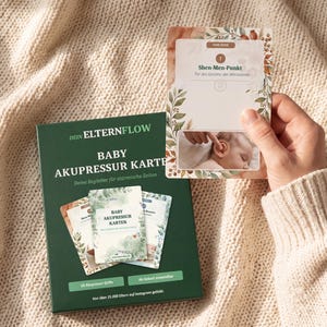 K&ouml;nnte beinhalten: Eine dunkelgr&uuml;ne Schachtel mit der Aufschrift DEIN ELTERNFLOW BABY AKUPRESSUR KARTEN und ein Set Lernkarten. Eine hochgehaltene Karte zeigt den Shen-Men-Punkt mit einer Abbildung eines massierten Babyohrs, umrahmt von botanischen Blattmotiven.