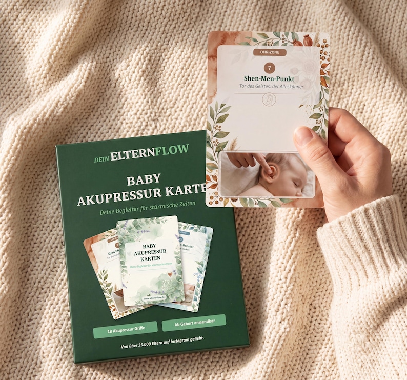 K&ouml;nnte beinhalten: Eine dunkelgr&uuml;ne Schachtel mit der Aufschrift DEIN ELTERNFLOW BABY AKUPRESSUR KARTEN und ein Set Lernkarten. Eine hochgehaltene Karte zeigt den Shen-Men-Punkt mit einer Abbildung eines massierten Babyohrs, umrahmt von botanischen Blattmotiven.