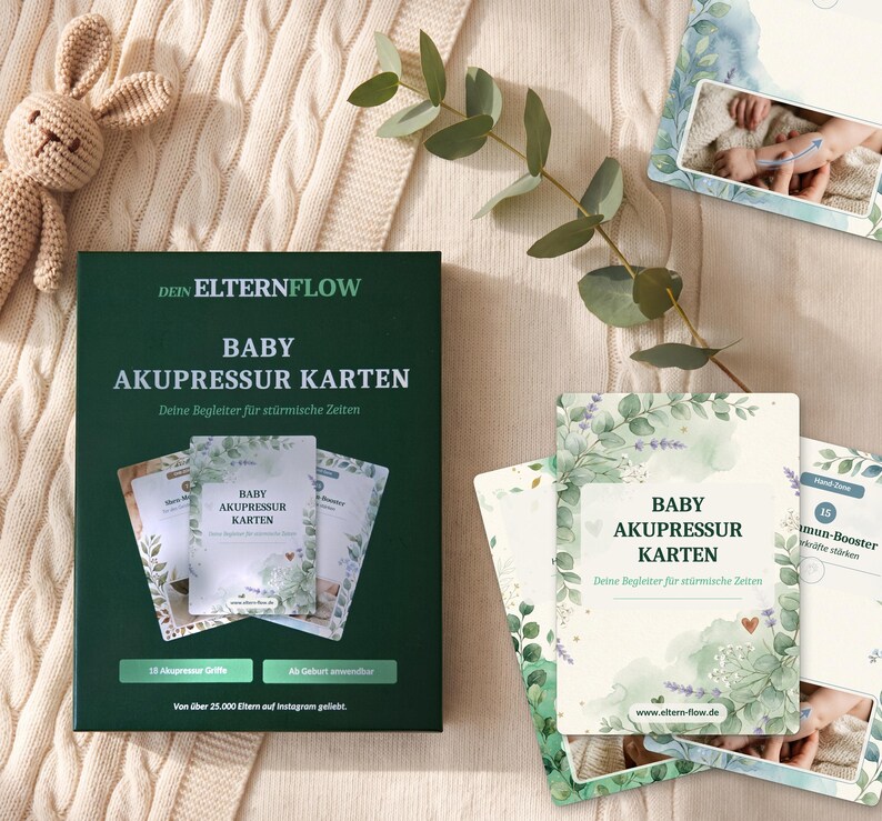 K&ouml;nnte beinhalten: Eine dunkelgr&uuml;ne rechteckige Schachtel mit der Aufschrift DEIN ELTERNFLOW BABY AKUPRESSUR KARTEN sowie mehrere Lernkarten mit botanischen Aquarellillustrationen, Text und Diagrammen zu Baby-Akupressurtechniken auf beigem Strickstoff.