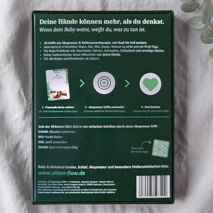 K&ouml;nnte beinhalten: Eine dunkelgr&uuml;ne rechteckige Schachtel mit deutschem Text und grafischen Anleitungen zur Baby-Akupressur. Die R&uuml;ckseite zeigt einen dreistufigen Prozess mit Symbolen, einem QR-Code, einem Barcode und Informationen zu 18 Akupressur-Karten.