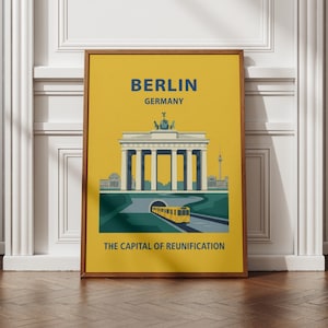 以下が含まれることがあります： 木製フレームに入った縦型のポスターで、黄色い背景に「BERLIN GERMANY」と「THE CAPITAL OF REUNIFICATION」の文字が書かれています。イラストにはブランデンブルク門とトンネルから出てくる黄色い電車が描かれています。
