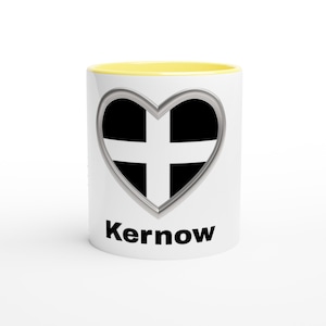 May include: White ceramic mug with a yellow interior. The mug features a heart-shaped design with the black and white Cornish flag, framed in silver. The word "Kernow" is printed in black below the heart.