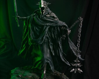 May include: A dark, armored figurine wearing a spiked helmet and a tattered, flowing cloak. The figure holds a long, straight sword in one hand and a spiked mace attached to a chain in the other, standing on a textured, rocky base with green lighting.