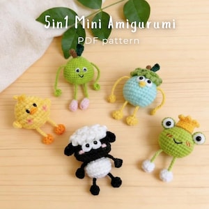 Puede incluir: Cinco pequeñas figuras amigurumi de ganchillo que incluyen un pollito amarillo, un personaje verde con forma de pera, una criatura azul claro con gorro verde, una oveja blanca y negra y una rana verde con corona. Texto 5in1 Mini Amigurumi PDF pattern.