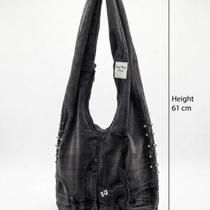 May include: A gray denim shoulder bag with a black cat applique and silver studs. The bag is 24 inches tall, 15 inches wide, and 3.5 inches deep. Features a label that reads "Hand Made Denim".