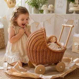 May include: A wicker doll's pram with wooden wheels and a handle. The pram contains a doll in a white dress with brown hair. A young child kneels beside the pram, looking at it with excitement. The scene is set for a baby shower.