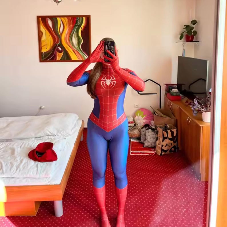 May include: A red and blue Spider-Man costume with a spider emblem on the chest. The costume features a red and blue colour scheme, with a web-like pattern on the red sections. The suit has long sleeves and covers the legs.