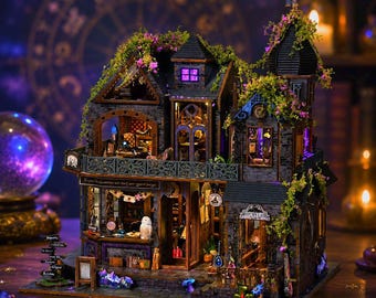 May include: A detailed miniature dollhouse with a witchy theme. The multi-story structure features a dark gray stone facade, ornate balconies, and is adorned with faux greenery and purple flowers. The windows are lit, and the shop sign reads "Explore the possibilities and start your magical journey."